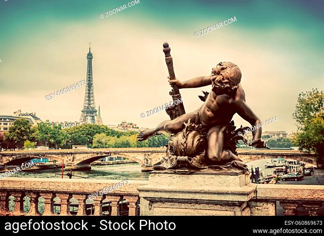 Artistic statue on Pont Alexandre III bridge in Paris, France. Seine river and Eiffel Tower. Vintage