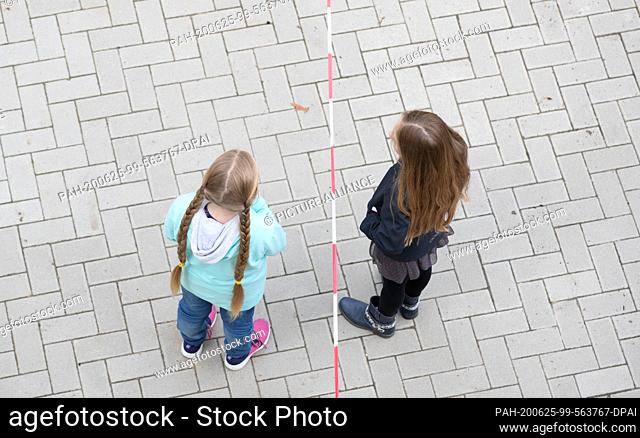 19 June 2020, Lower Saxony, Osnabrück: Pupils stand in front of a barrier tape in the playground of a primary school. Due to corona regulations