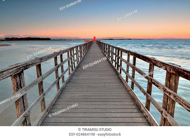 Wide angle shot of wooden pier with a red lighthouse