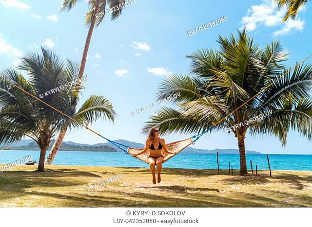Female relaxing in a hammock on a tropical beach. Enjoying beach life on Palawan island, Philippines