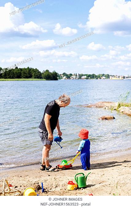 Grandfather playing on beach with grandson