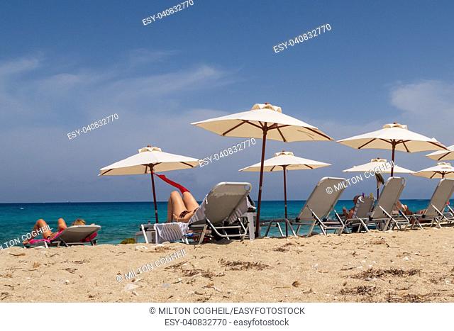 Tourists relaxing on sunlounger on the beach on Lefkada island, Greece