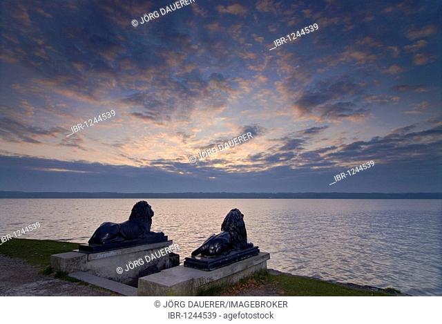 Two metal lions overlooking Lake Starnberg in front of a colorful sunrise, Bavaria, Germany, Europe