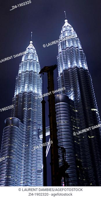 Petronas towers Kuala Lumpur at night with construction crane on the foreground