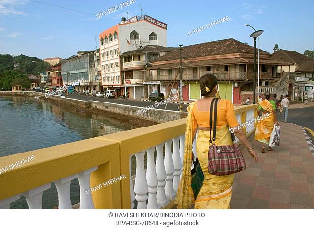 Woman in yellow saree going to work over Old Pato bridge ;  Yellow bridge on the Mandovi River ;  Mahatma Gandhi Road ;  old Portuguese structure ;  Panjim ;...