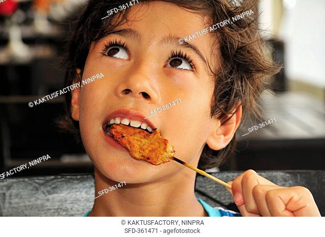Boy eating chicken satay