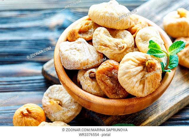 Delicious dried figs in a wooden bowl closeup, selective focus