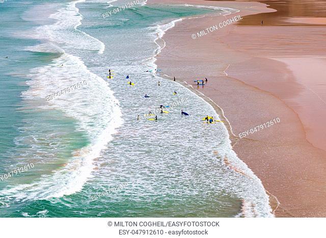 Surfers in the waves off Mawgan Porth Beach, Cornwall, UK