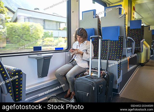 Woman Travel in a Train and Using Phone with Her Luggage in Ticino, Switzerland