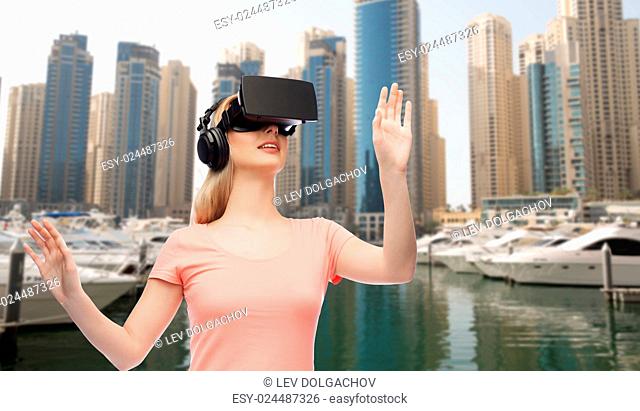 technology, virtual reality, entertainment, travel and people concept - happy young woman with virtual reality headset or 3d glasses and headphones playing game...