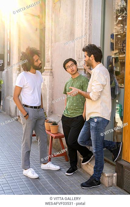 Three young men talking in the city