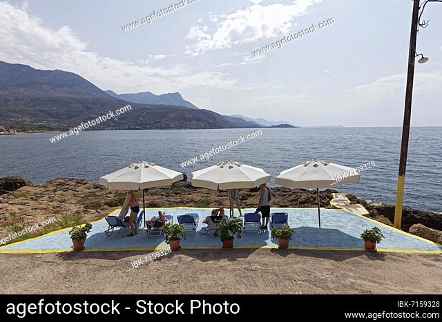 Small bathing place with umbrellas on stony coast, Agios Nikolaos, Mani Peninsula, Messinia, Peloponnese, Greece, Europe