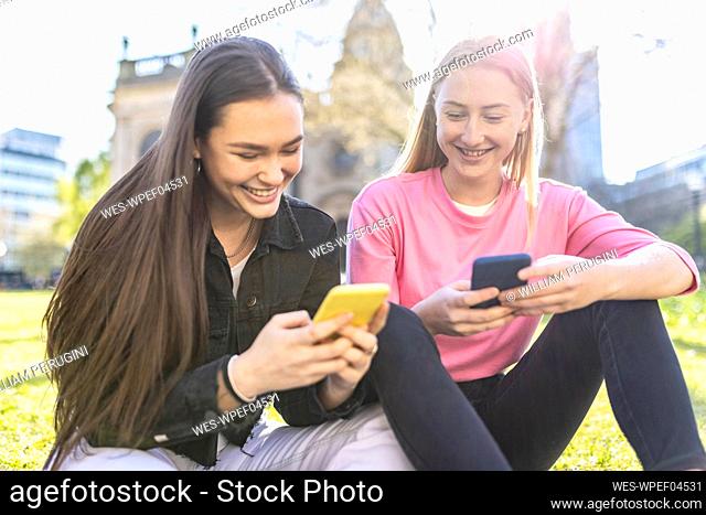 Smiling women using smart phone at park