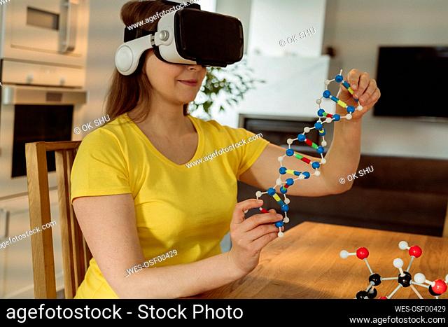 Woman with VR goggles examining helix model at home