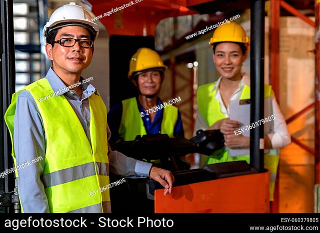 Portrait of Asian warehouse manager and his team worker with forklift truck in background. Reopening business warehouse inventory technology and logistic...