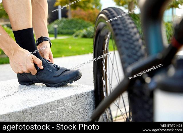Cyclist tying shoelace by bicycle