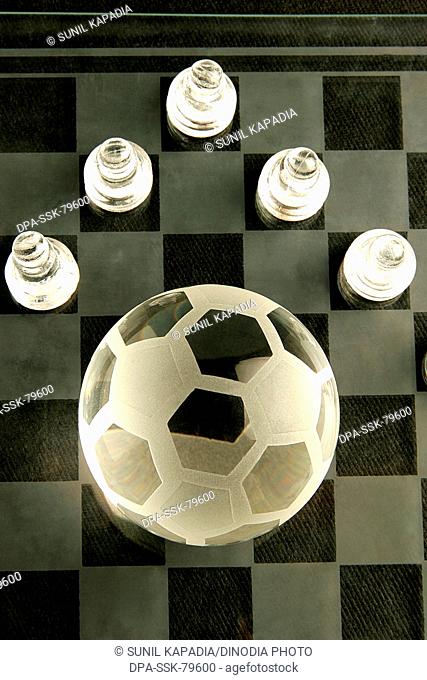 Ball of football made of glass on glass chess board with its pawns as players