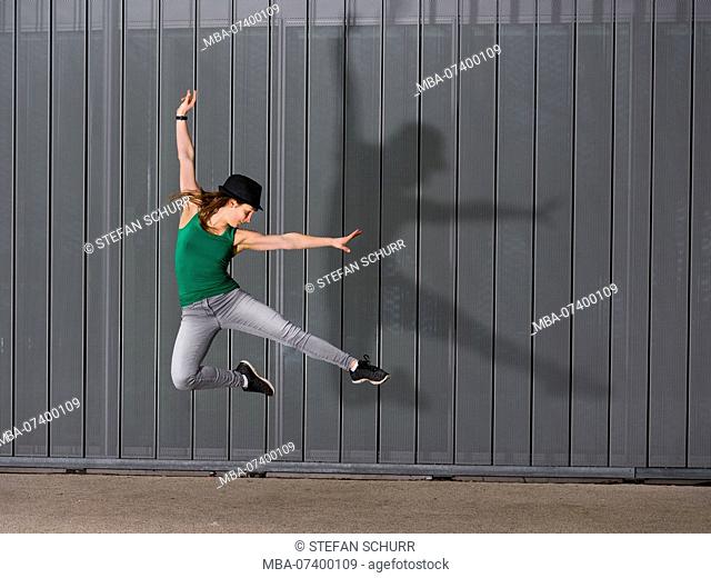 Jumping teenager with silhouette, lifestyle, 18 years old, female, urban environment