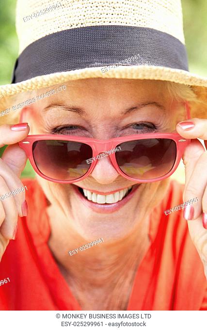 Head And Shoulders Portrait Of Smiling Senior Woman Wearing Sunglasses