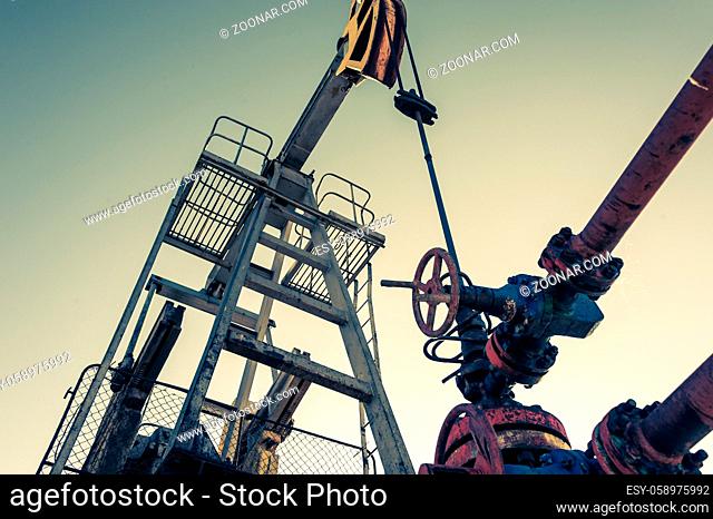 Oil pumpjack, industrial equipment on sunset sky background. Rocking machines for power generation. Extraction of oil. Petroleum concept