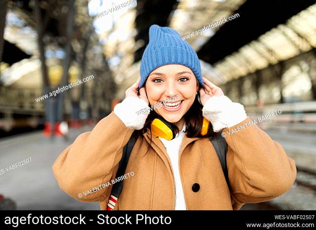 Portrait of happy young woman wearing wooly hat at the train station