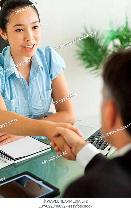 Well-dressed businesswoman shaking man's hand in her office