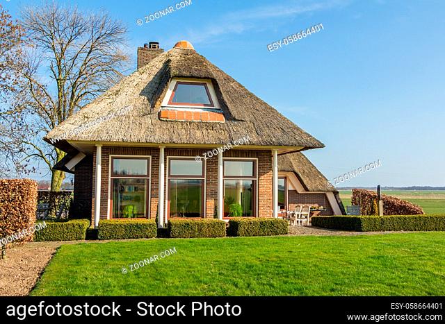Overijssel, Netherlands - March 16, 2014: Cozy cottage with thatched roof on a dike near in Holland