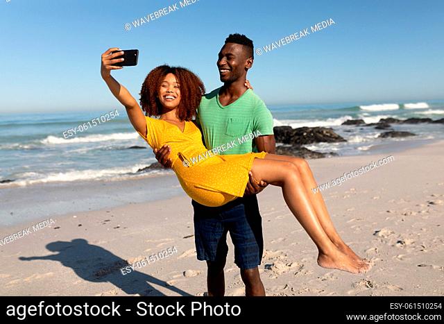 Mixed race couple taking selfies on the beach