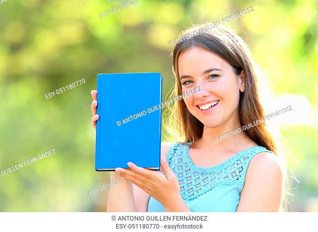 Happy woman showing a blank paper book cover in a park
