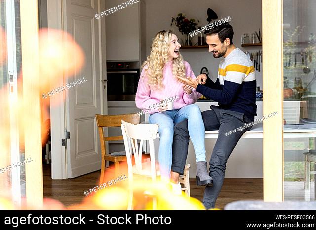 Playful couple sitting on table at home