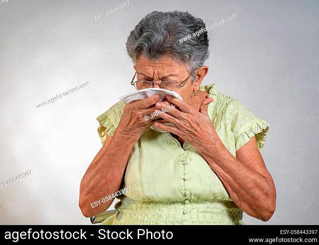 An old woman sneezing and covering his mouth and nose