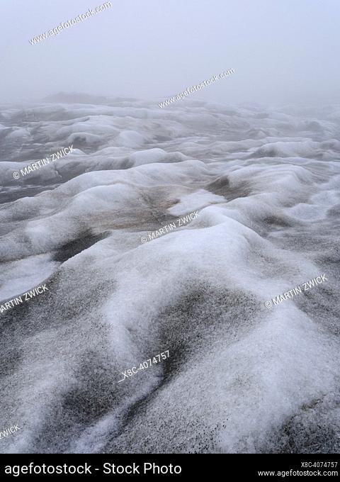 The brown sediment on the Greenland ice is created by the rapid melting of the ice. Landscape of the Greenland ice sheet near Kangerlussuaq