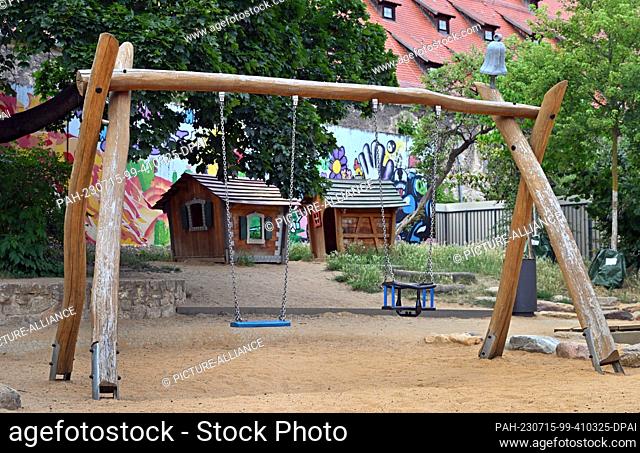 PRODUCTION - 13 July 2023, Erfurt: A swing and playhouses at the playground in Glockengasse. In Erfurt, there are already boxes with sand toys at three...