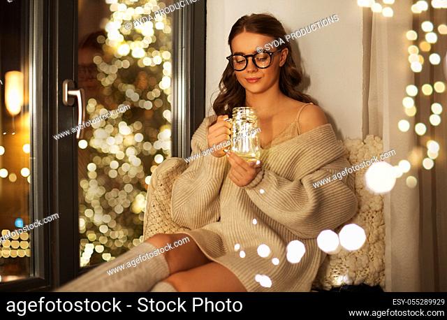 woman with christmas garland lights in glass mug