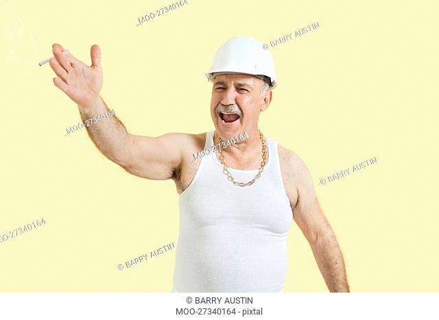Senior male constructor shouting over yellow background