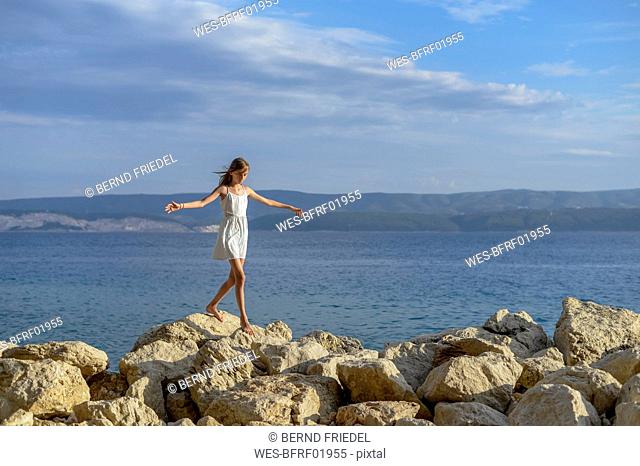 Croatia, Lokva Rogoznica, girl balancin barefoot on rocks