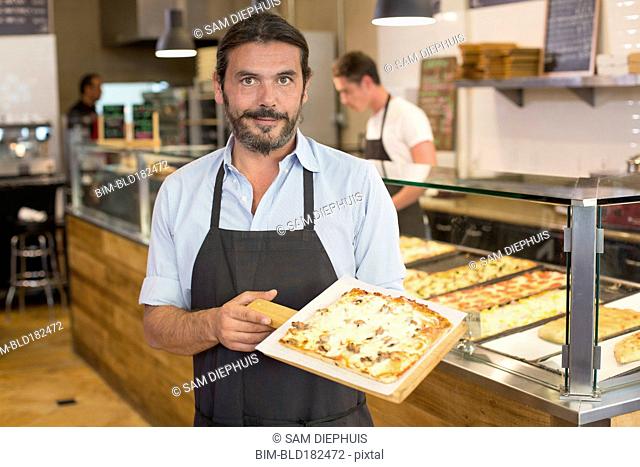 Server holding pizza in cafe