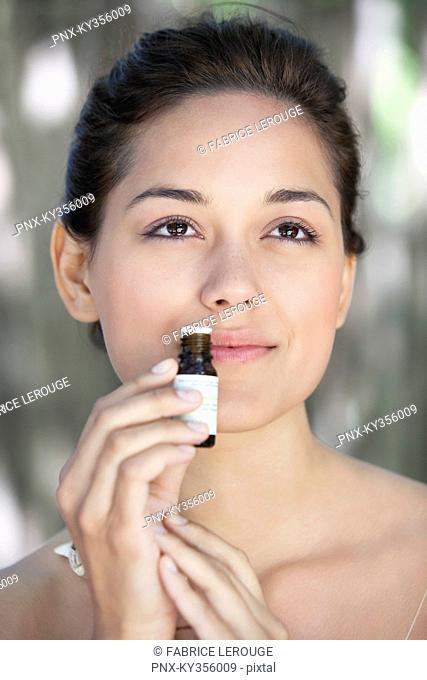 Young woman smelling aromatherapy oil