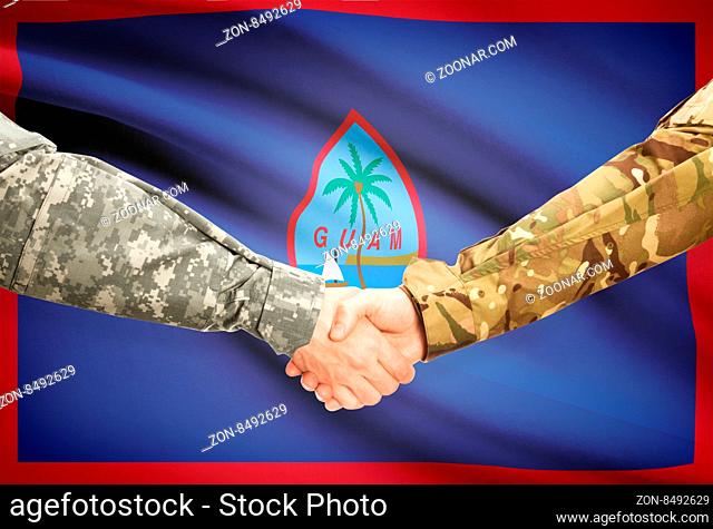 Soldiers shaking hands with flag on background - Guam