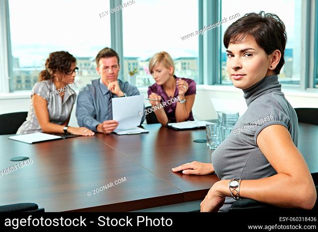 Panel of business people sitting at table in meeting room conducting job interview. Applicant looking at camera