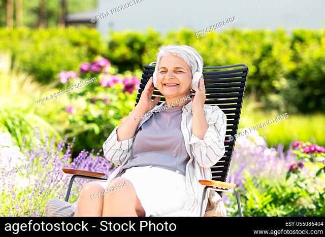 happy senior woman with headphones at garden