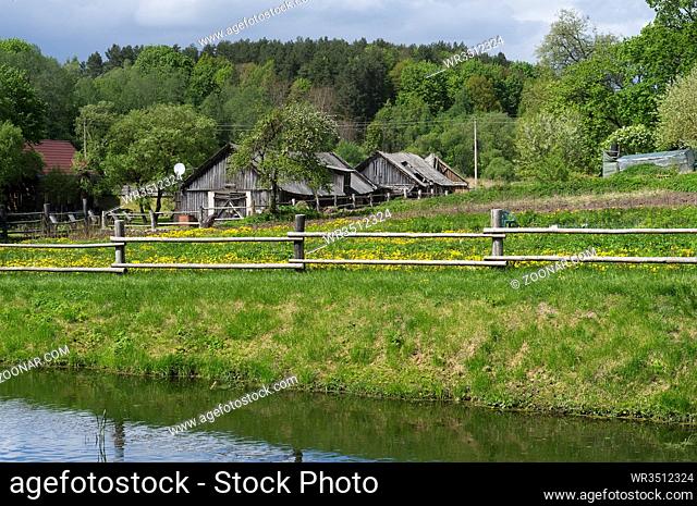 Retro wooden European village on lake bank spring landscape