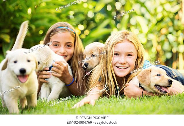Adorable Cute Young Girls with Golden Retriever Puppies