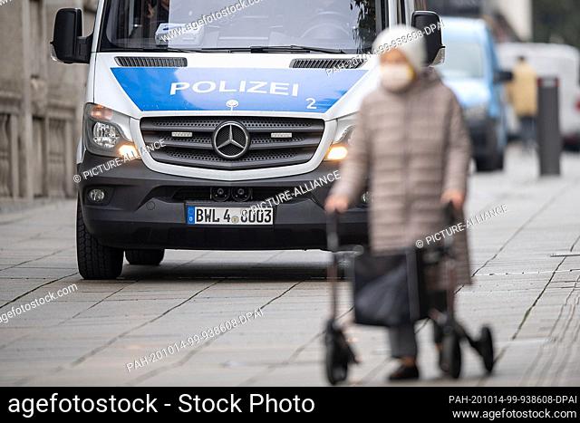 14 October 2020, Baden-Wuerttemberg, Stuttgart: A woman with mouth and nose protection walks past a police car on Königstraße with the help of a rollator