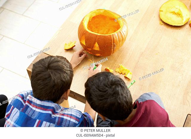 Siblings carving pumpkin in dining room