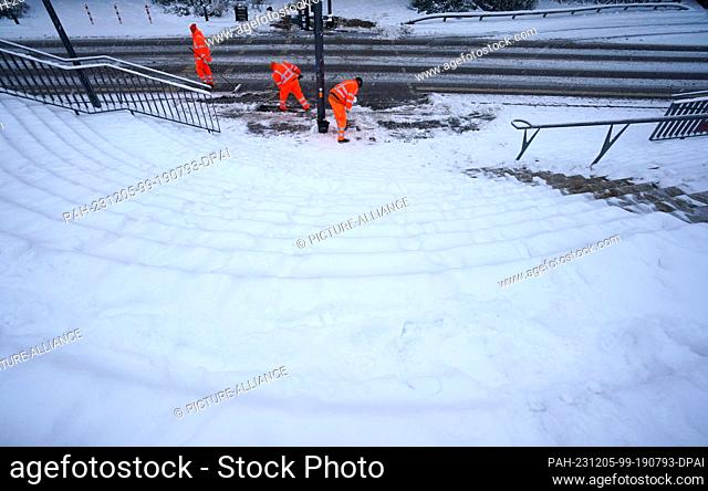 05 December 2023, Hamburg: City cleaning staff push snow away at a traffic light at the Landungsbrücken. Photo: Marcus Brandt/dpa