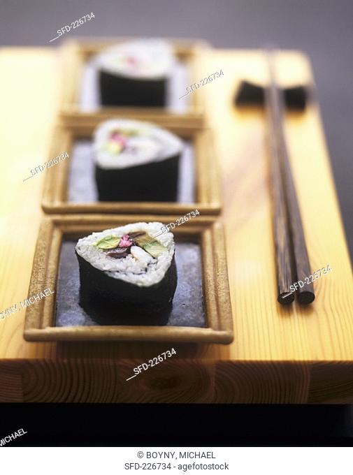 Futo maki in small bowls on wooden board