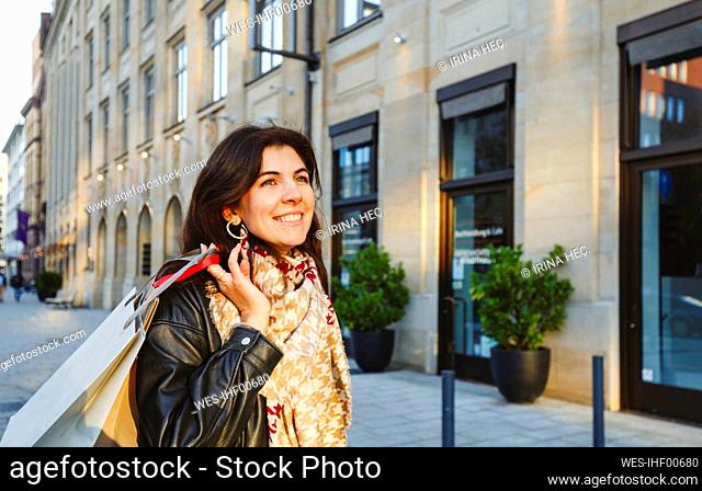 Happy woman holding shopping bags at city street