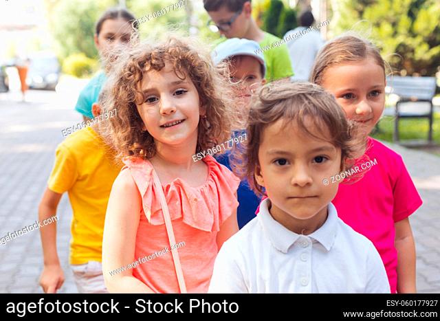 Portrait of happy preschool kids posing closely together outdoors, looking at camera. Lovely boy and girls outdoors at summer camp