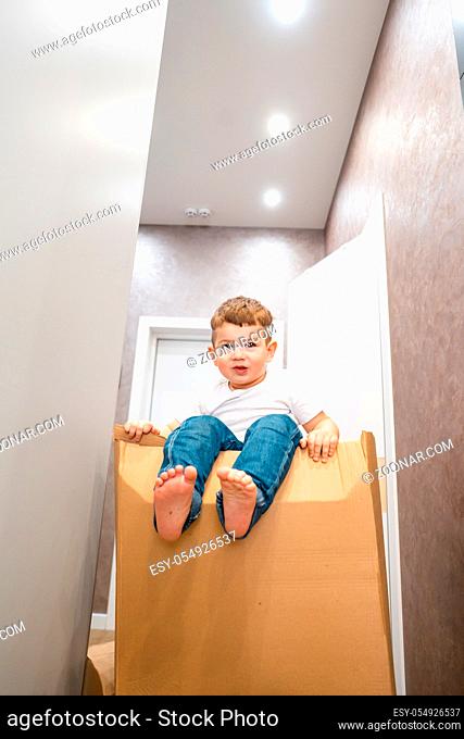 Cute little boy sitting on a cardboard box in the corridor